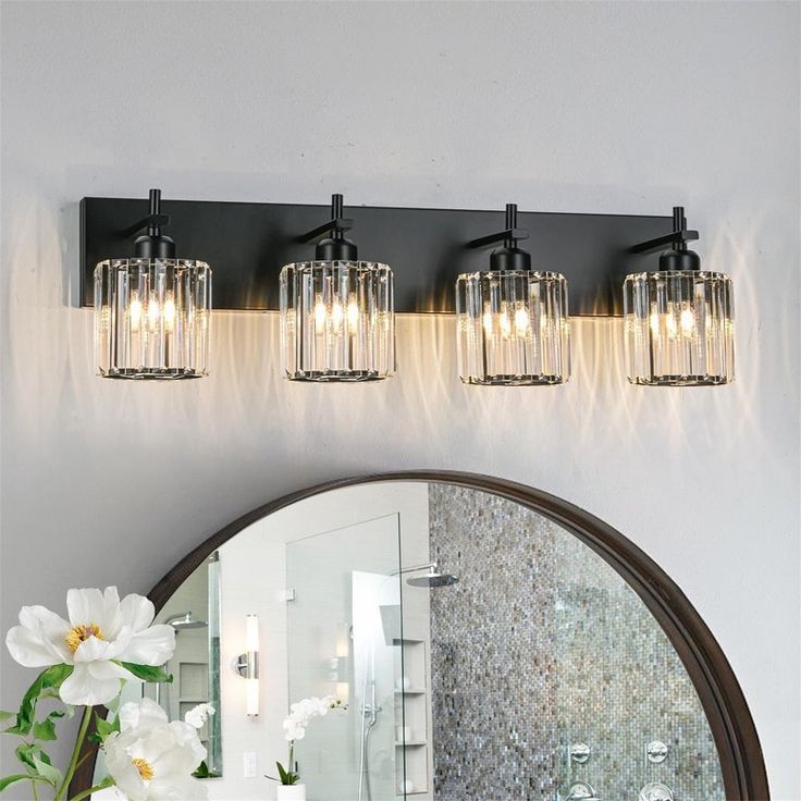 a bathroom vanity with three lights and a mirror on the wall next to a flower vase