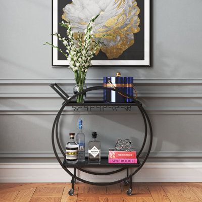 a table with books and drinks on it in front of a wall mounted art piece