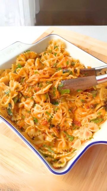 a bowl filled with pasta and sauce on top of a wooden table