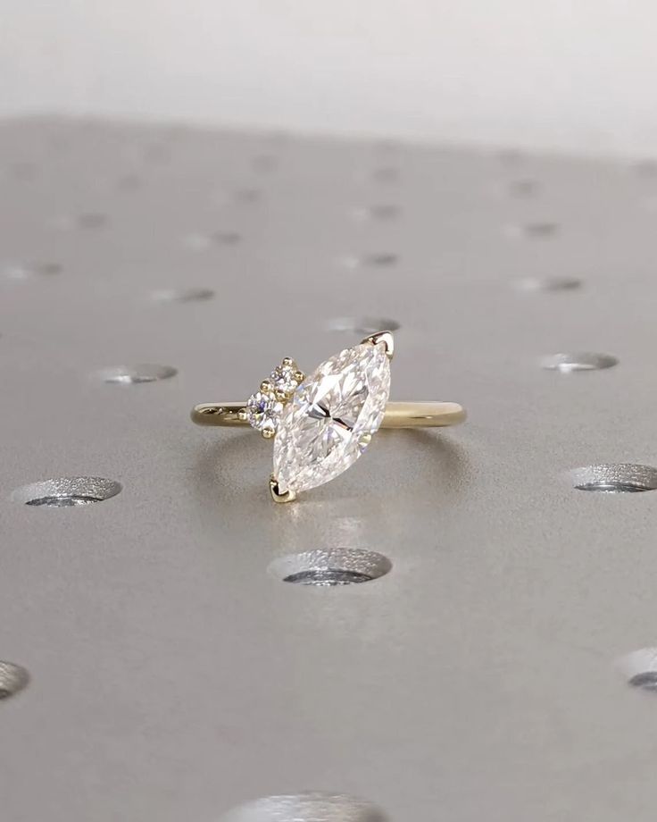 an engagement ring with a pear shaped diamond on it's side, surrounded by small bubbles