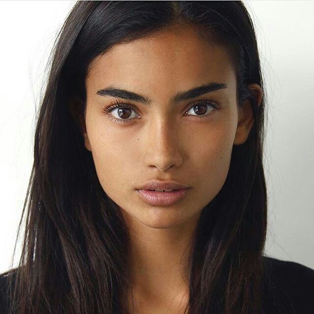 a close up of a person wearing a black shirt and long hair with brown eyes