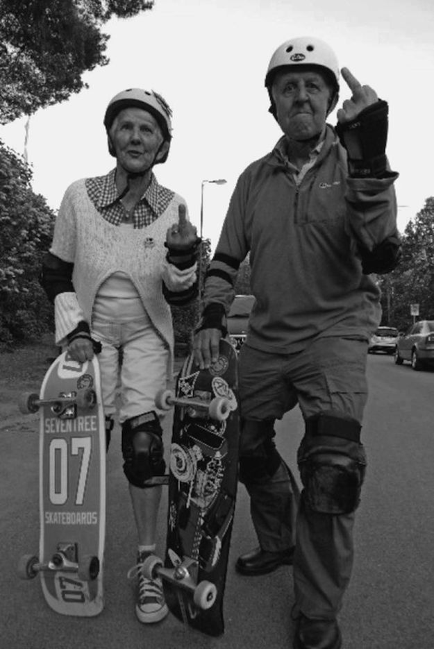 an older man and woman walking down the street with skateboards on their feet,