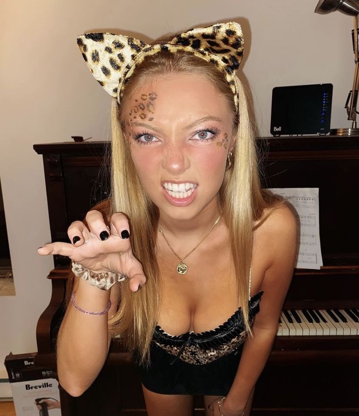 a woman with her hands in the air and wearing a leopard print cat ears headband