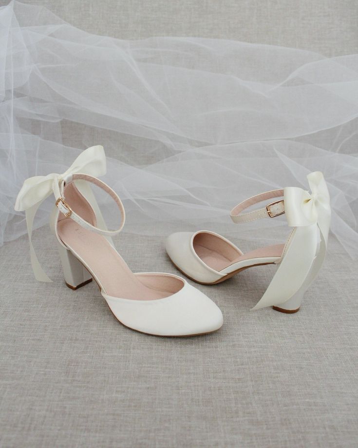 a pair of white shoes with bows on the toes and heels are sitting next to each other