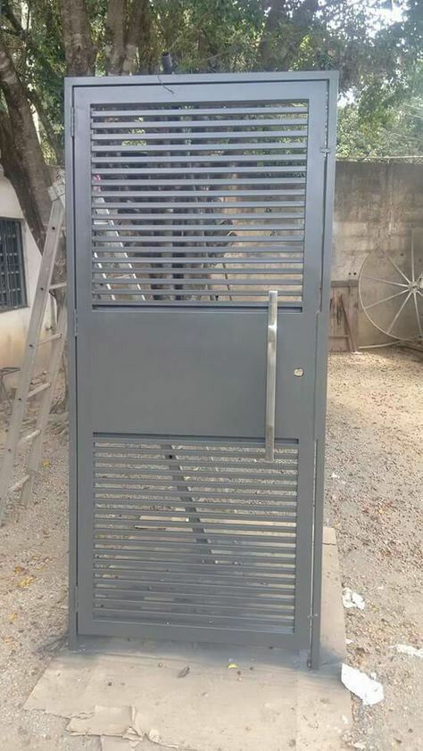 an old metal door in the middle of a dirt lot with stairs leading up to it