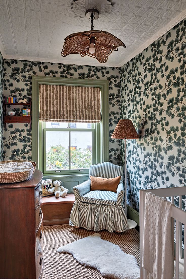 a baby's room with floral wallpaper and furniture