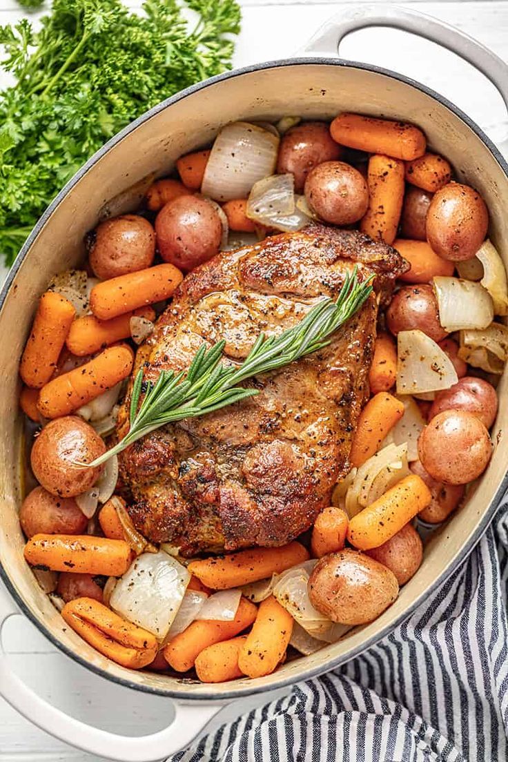 a pot filled with meat, potatoes and carrots on top of a white table