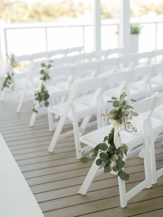 a row of white chairs sitting on top of a wooden floor