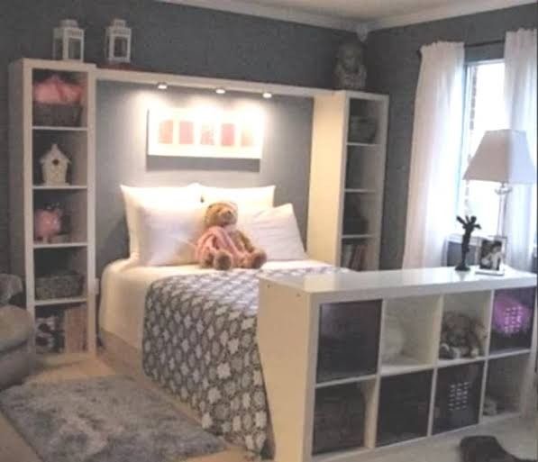 a teddy bear sitting on top of a bed next to a book shelf in a bedroom