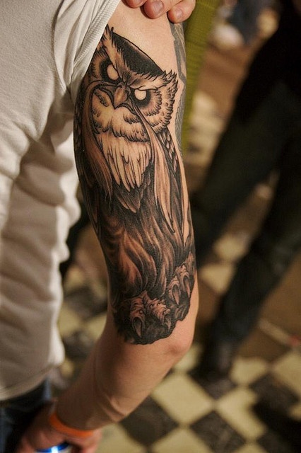 an owl tattoo on the arm of a man