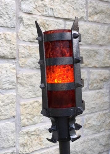 a traffic light sitting on top of a metal pole in front of a brick wall