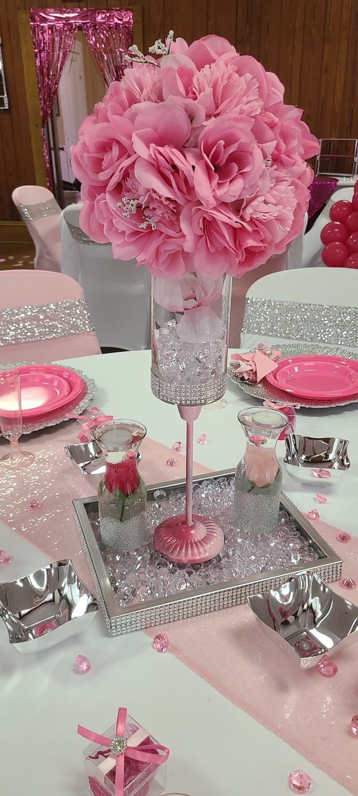 a table with pink flowers in a vase and silverware on it's centerpieces