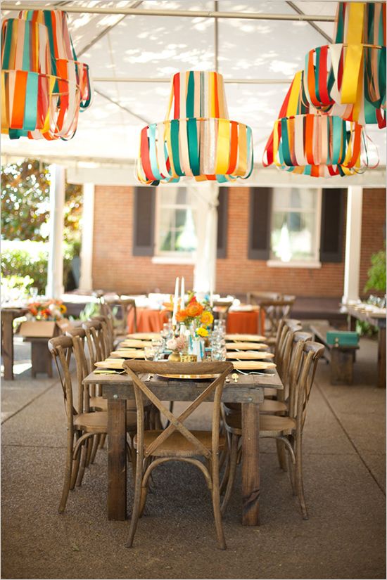 an outdoor dining area with chairs, tables and umbrellas hanging from the ceiling above