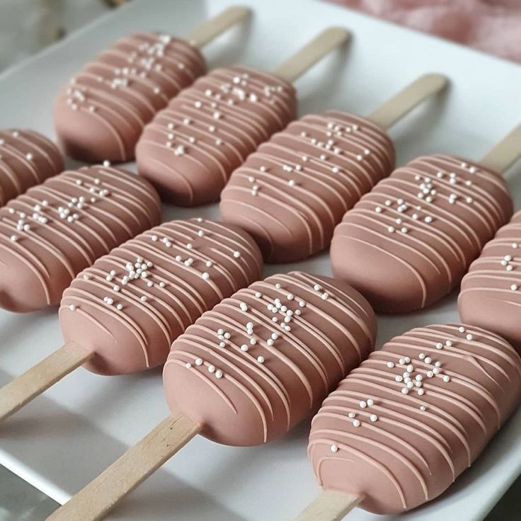 there are many pink and white desserts on the tray together with wooden skewers