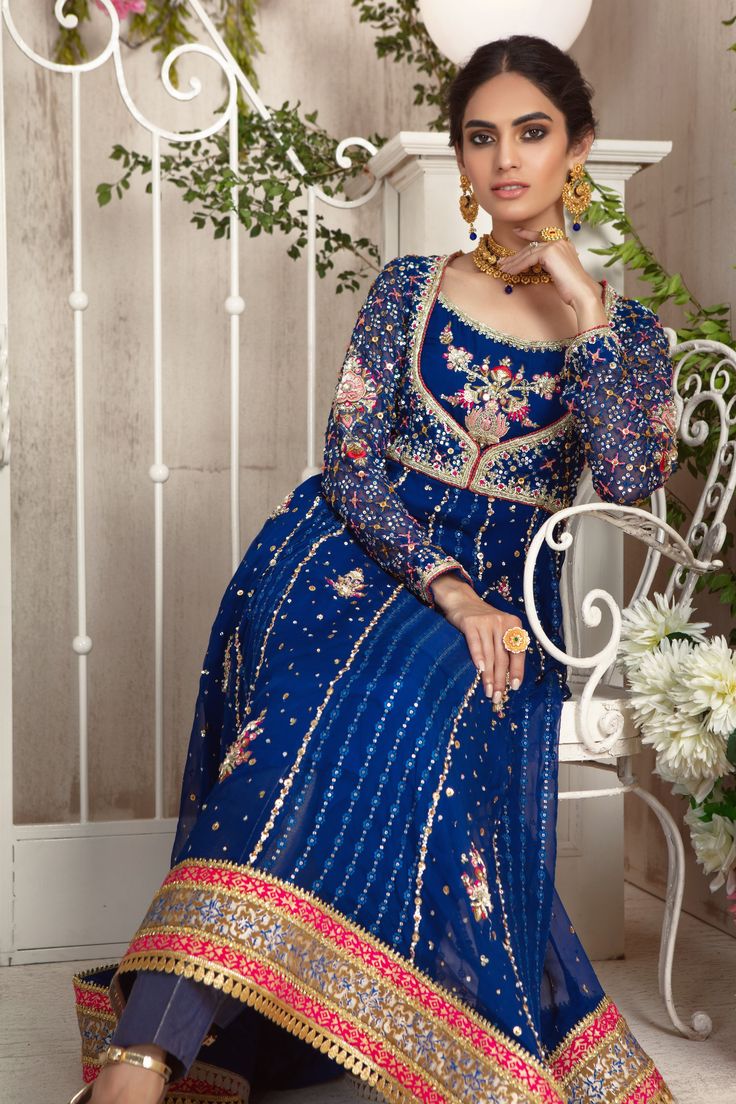 A traditional kalidar peshwas in beautiful Royal Blue hue featuring multi color silk thread embroidery and stunning zardozi details of dabka, naqshi, sequins, pearls and beads. Hand block printed borders further enhanced with gota details on hem. This kalidar is paired with brocade pant and glistening heavily sequin embellished dupatta completes the look. Regal and timeless piece for all wedding festivities. Shirt Fabric: Pure Embroidery Chiffon and Pure Plain ChiffonShirt Length: 50” (customisa Reception Anarkali Set With Dabka Work For Navratri, Blue Anarkali Set With Zari Work For Transitional Season, Transitional Blue Anarkali Set With Zari Work, Transitional Anarkali Lehenga With Dabka, Designer Blue Anarkali Set With Dupatta, Transitional Anarkali Lehenga With Dabka Details, Navratri Designer Dabka Choli, Designer Blue Sharara With Zari Work, Anarkali Jamawar Set With Zari Work