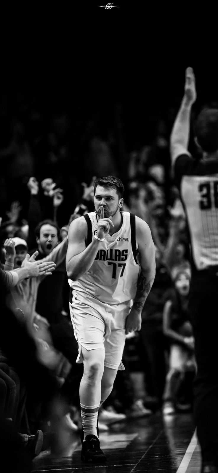 a black and white photo of a basketball player walking on the court with his hands in the air