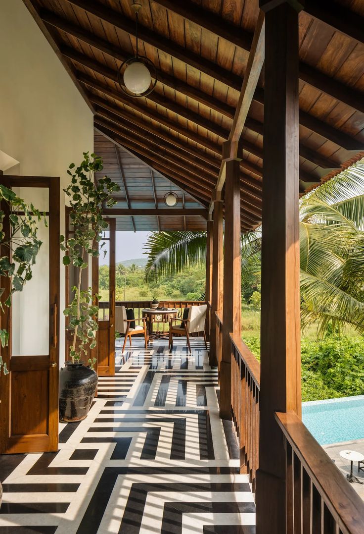 an open porch with black and white tiles on the floor next to a swimming pool