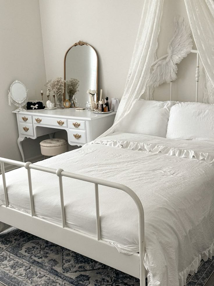 a white bed sitting in a bedroom next to a dresser with a mirror on top of it