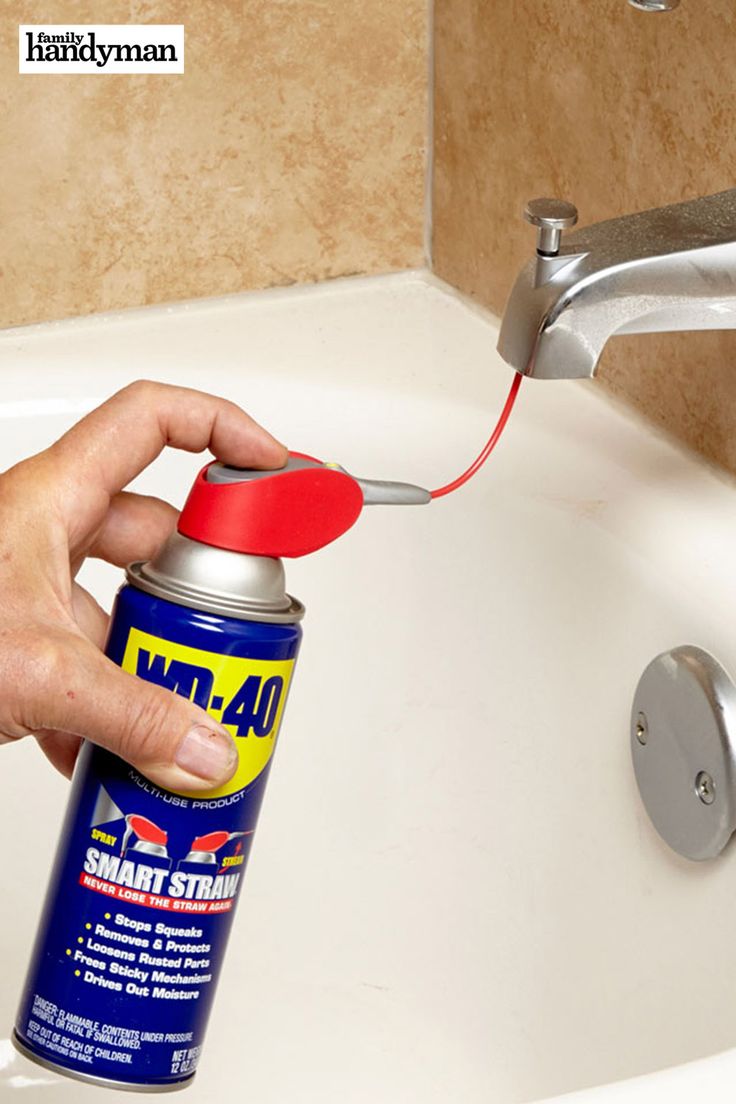 a hand holding a can of spray paint in front of a sink faucet