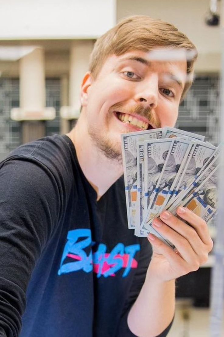 a man is holding money in one hand and looking at the camera with an excited look on his face