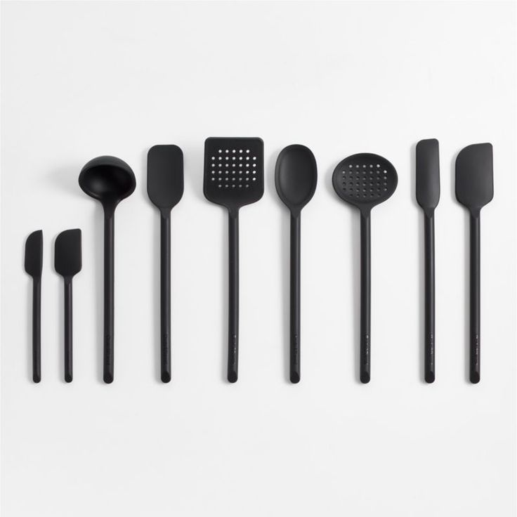 black kitchen utensils lined up on a white surface