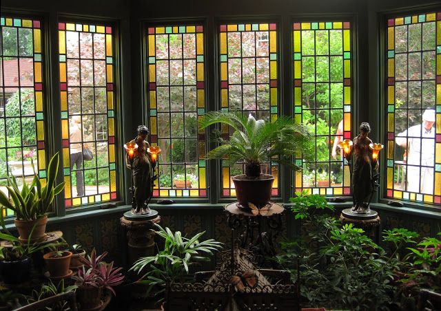 a room filled with lots of windows covered in stained glass and potted plants next to each other