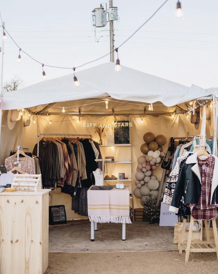 a tent with clothes and other items on display at an outdoor flea market in the evening