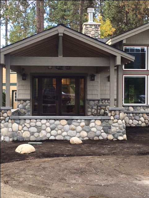 a house that is made out of rocks and has a front porch on the side