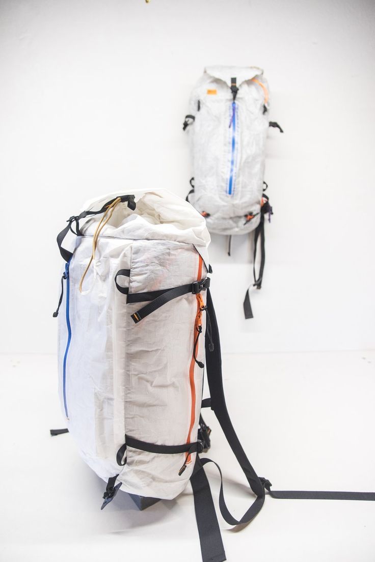 two backpacks sitting next to each other on top of a white floor with black straps