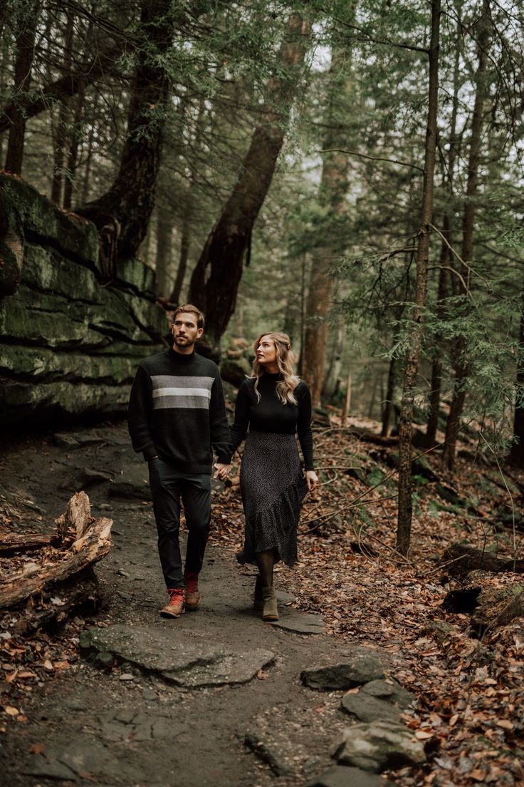 an engaged couple walking through the woods together