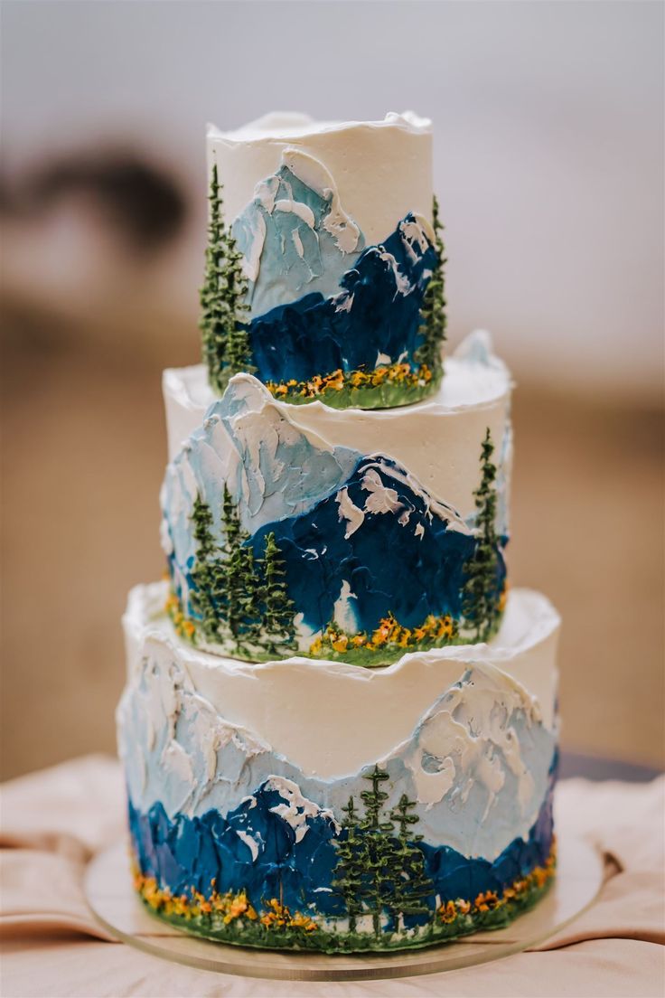 three tiered cake decorated with mountains and trees