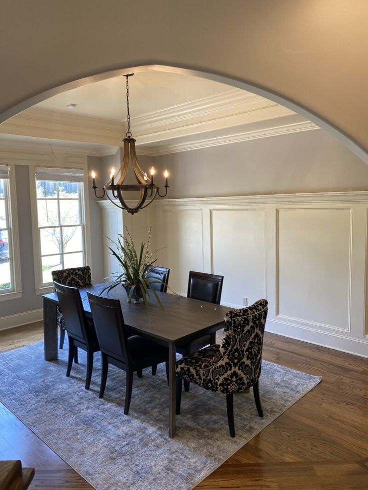 a dining room table with chairs and a chandelier hanging from it's ceiling