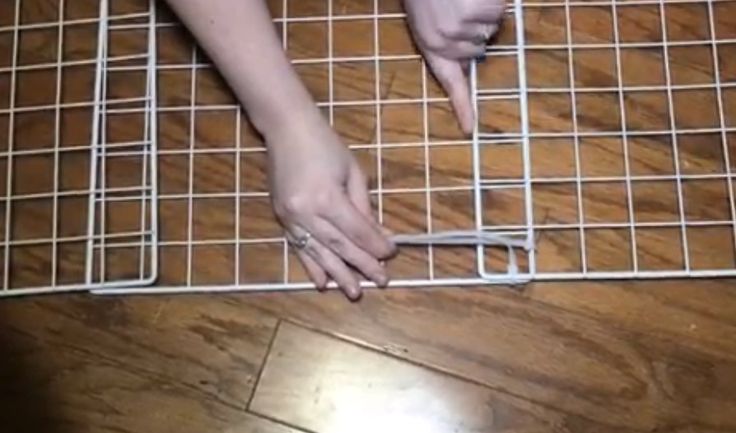 two hands reaching for something on the ground near a wire grid area that is being held by someone's hand