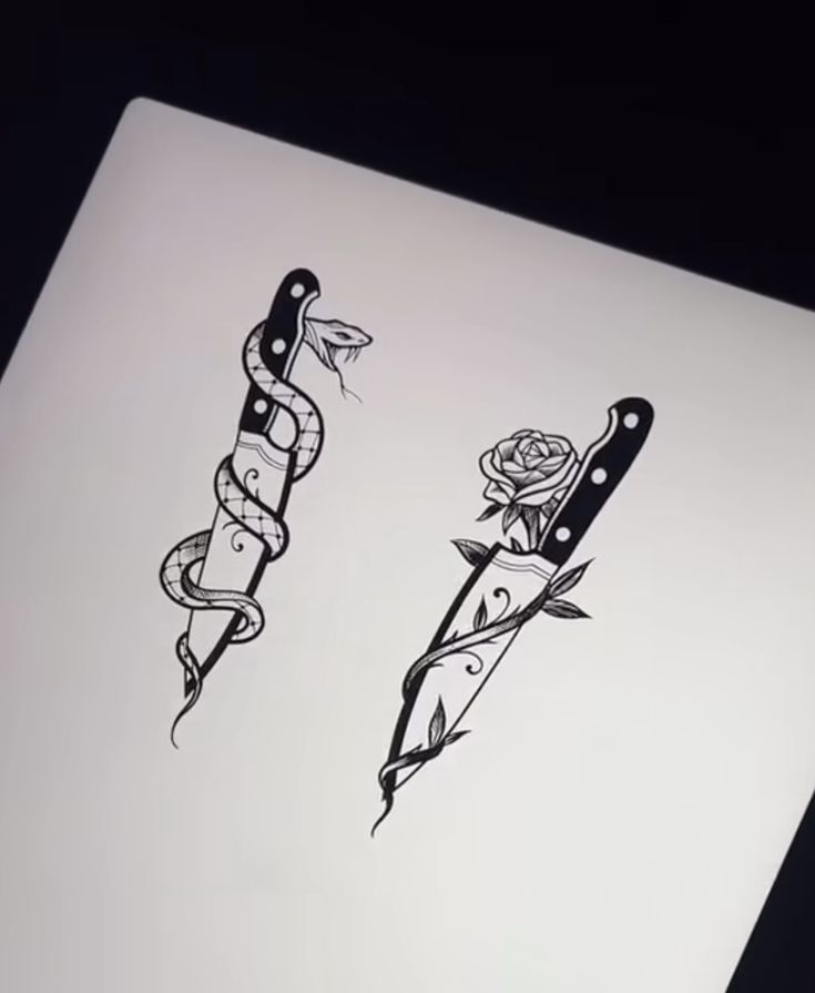 two knives with tattoos on them sitting next to each other