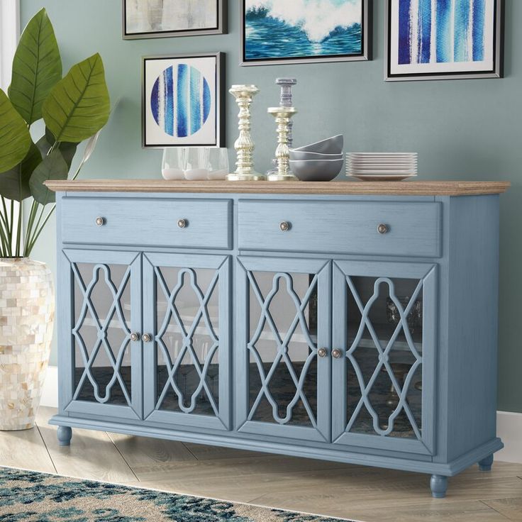 a blue sideboard in a living room with pictures on the wall