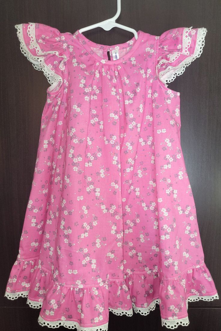 Cute baby frock in soft cotton print with tiny bunches of grey and white flowers in a pink background.   A full figure dress with crease at front of round neck. A little button closes the partial opening at back. Double frill at at medium armhole and a ruffle at hem. Both parts decorate with a white eyelet trim. Grey And White Flowers, Red Bow Dress, Baby Girl Angrakha Frock Design, Full Figure Dress, Vintage Baby Dresses, Figure Dress, Baby Frock, Kids Frocks, Cherry Hill