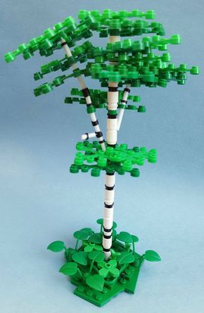 a green and white tree made out of legos on a blue background with leaves