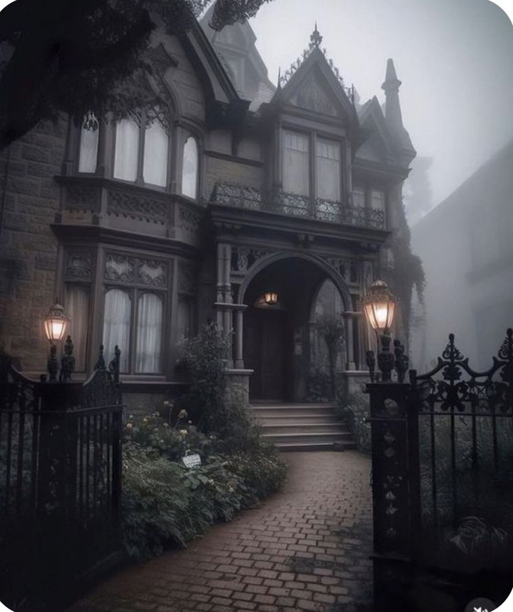 an old victorian house in the fog with two lights on it's front door