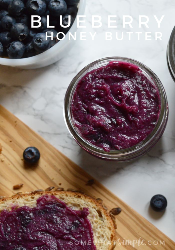 blueberry and honey butter in jars next to bread on a cutting board with fresh blueberries