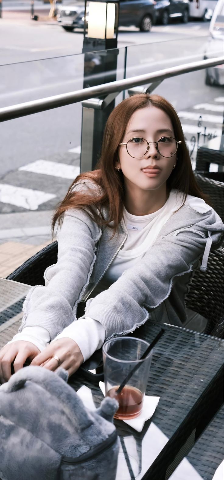 a woman sitting at a table with an elephant purse on it's lap and glasses in her hand