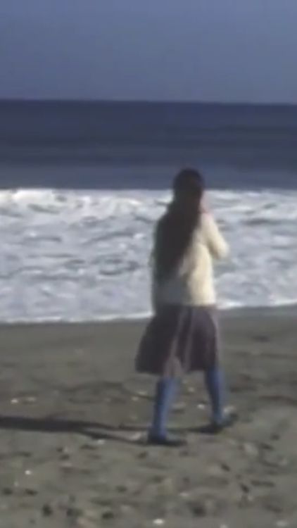 the woman is walking on the beach near the water