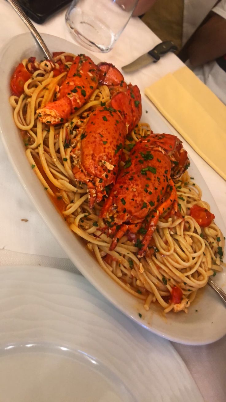 lobsters and spaghetti on a white plate at a restaurant