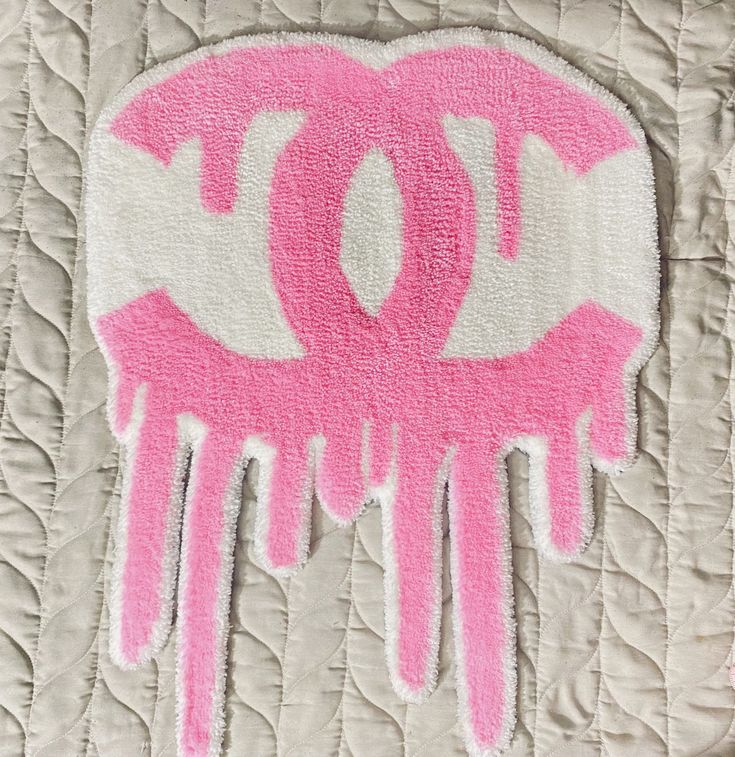 a close up of a pink and white object on a quilted surface with the word dc painted on it