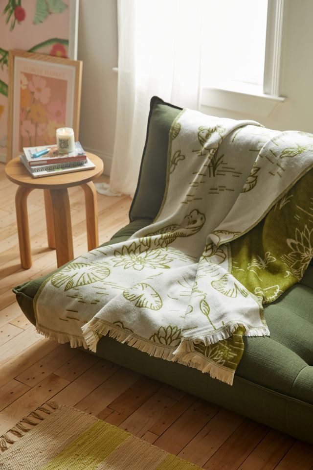 a green couch with a blanket on top of it