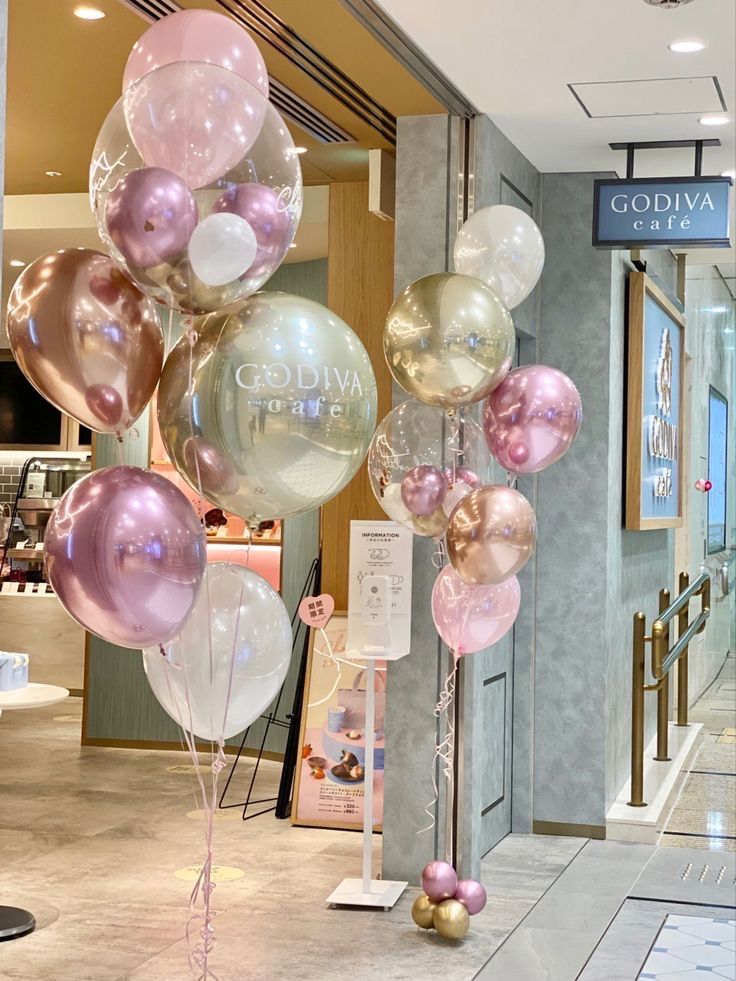 a bunch of balloons that are on the ground in front of a storefront window