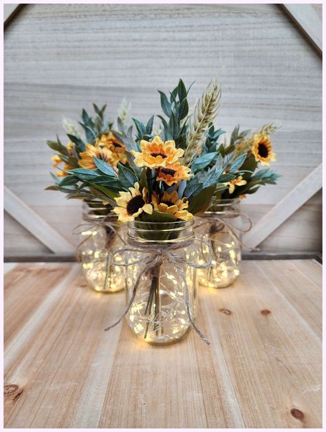 three mason jar vases with sunflowers and greenery in them on a wooden table