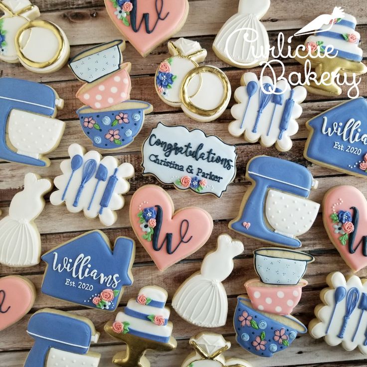 decorated cookies are arranged on a wooden surface with the words congratulations written in blue, pink and white