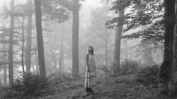 a woman standing in the middle of a forest with fog on her face and head