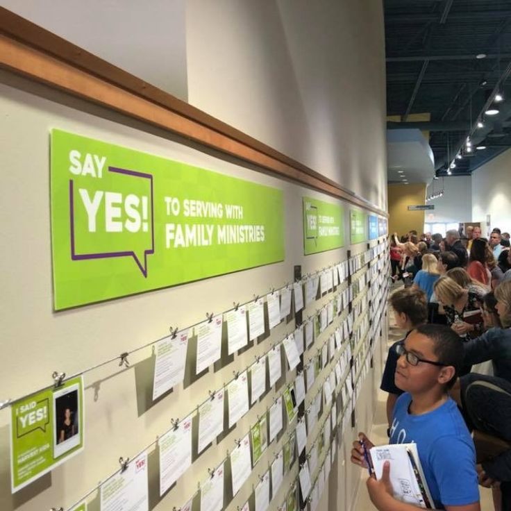 a group of people standing in front of a wall with sticky notes attached to it