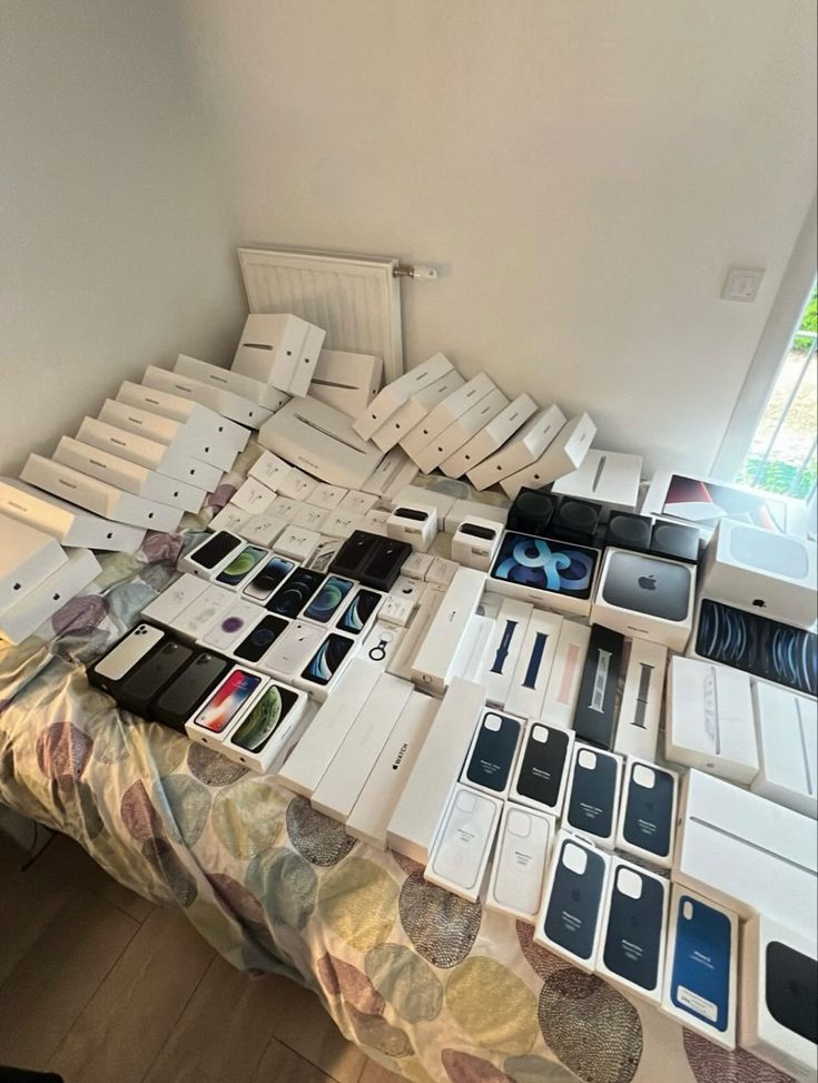 a bed covered in lots of cell phones sitting on top of each other next to a window